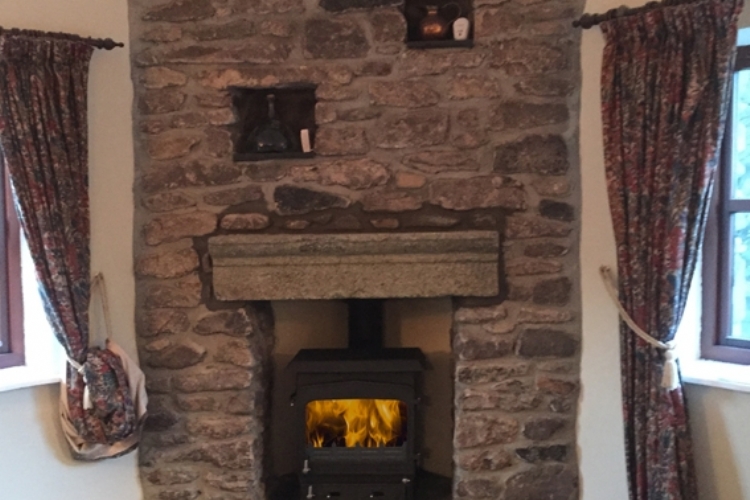 Woodwarm stove in a traditional stone fireplace